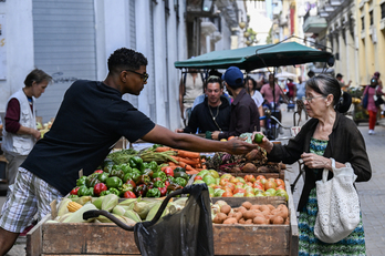 Una mujer compra verdura a un vendedor callejero en La Habana.