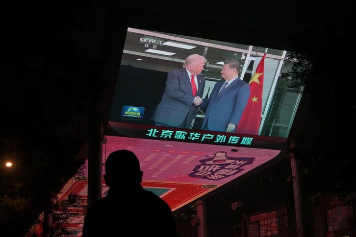 En una pantalla se ve la cobertura informativa de la reunión entre el presidente de Estados Unidos, Donald Trump, y el presidente de China, Xi Jinping, en Corea del Sur, frente a un centro comercial de Pekín, el 30 de octubre de 2025.