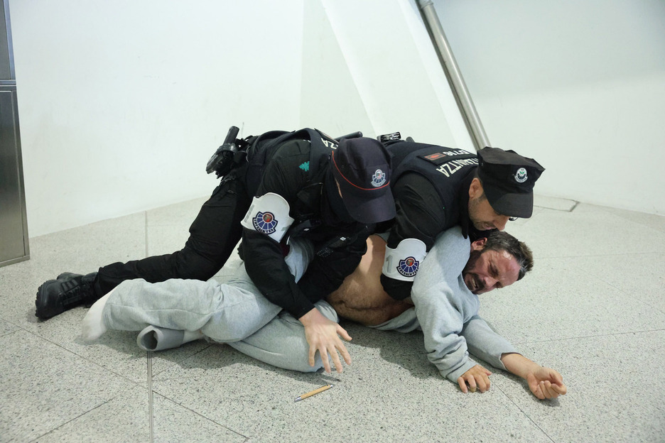 Dos ertzainas reducen a un miembro de la flotilla. 