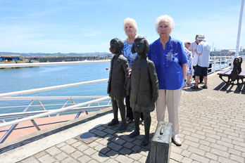 Dos de aquellas ‘niñas de la guerra’, este sábado en Santurtzi junto a las estatuas que rememoran aquella triste marcha.