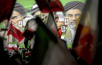 Jarraitzaileak, Irango banderak astintzen, hautatu berri duten Mojtaba Khamenei aiatolaren erretratuaren aurrean.
