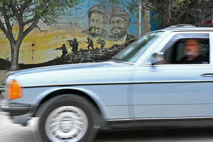Residentes desplazados pasan en coche junto a un mural que representa a los líderes de Hizbulah mientras regresan a la ciudad de Nabatieh, en el sur de Líbano, el 18 de abril de 2026.
