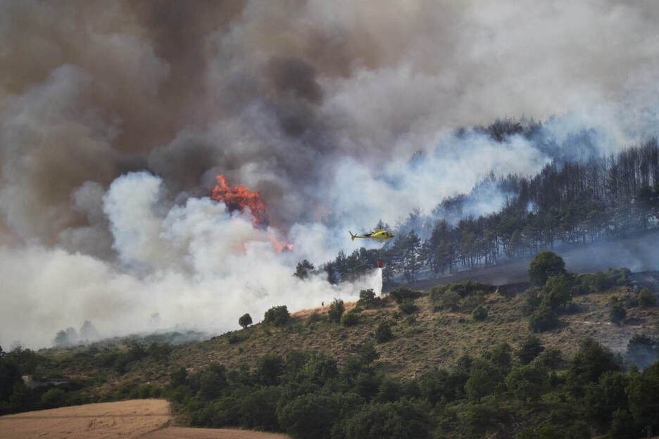 Un helicóptero sobrevuela la zona en llamas.