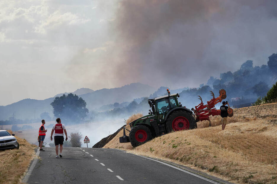 Una cosechadora parece vigilar el fuego desde el campo de cereal cercano.
