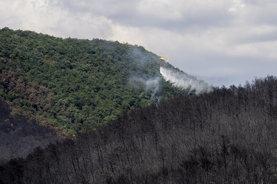 Un helicóptero descarga agua en la zona del incendio.