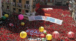 En la página anterior, la plaza con los pañuelos en alto se prepara para el estallido del cohete. sobre estas líneas, apreturas durante la celebración del txupinazo en la plaza del Castillo.