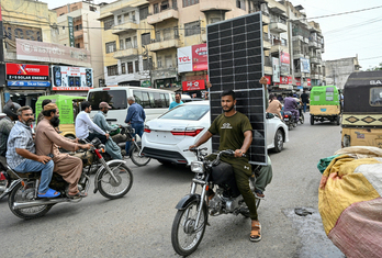Un hombre transporta un panel fotovoltaico en las calles de Karachi.