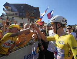 Pogacar saluda a un joven aficionado en la cima del Alpe d’Huez.