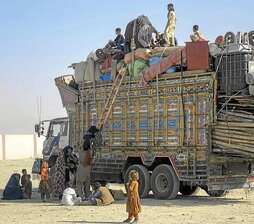 Refugiados afganos suben en Chaman a un camión con sus pertenencias para ser deportados.
