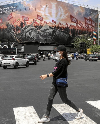 Una mujer pasa ante un mural contra EEUU, en Teherán.
