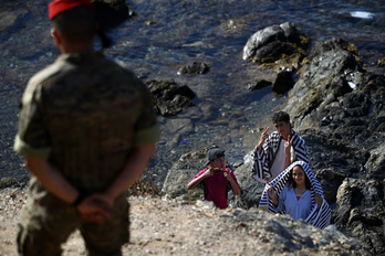 Menores llegados de Marruecos, en una playa de Ceuta ante un soldado español este pasado domingo.