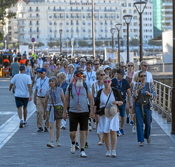 Turista multzo bat Donostiako kaira inguratzen.