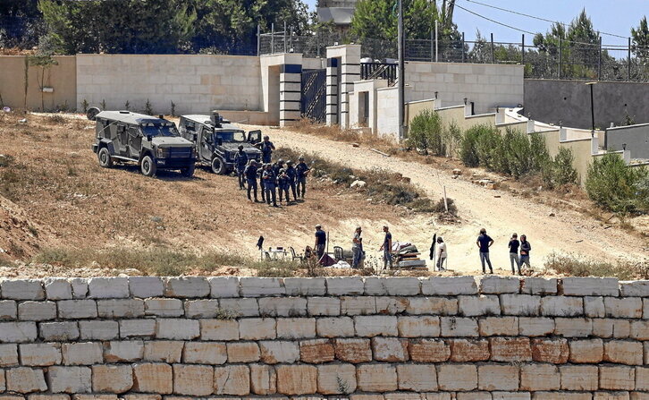 Soldados y colonos israelíes, frente a una de las casas de familias palestinas asediadas en Qusra.