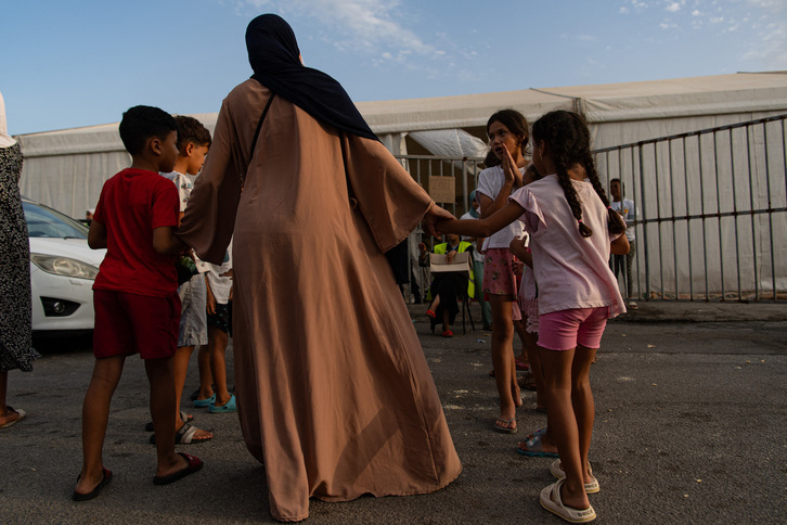 Mujeres y niñas migrantes esperan ante la oficina de una ONG que ofrece asistencia en Ceuta.