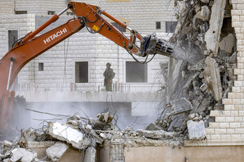 Un soldado israelí observa cómo una excavadora militar derriba un edificio palestino en Nablus.