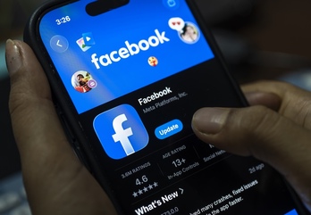 Una persona sostiene un teléfono con la aplicación de Facebook