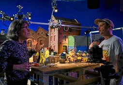 Claire Rolls charla con un compañero frente a uno de los decorados de su último film.