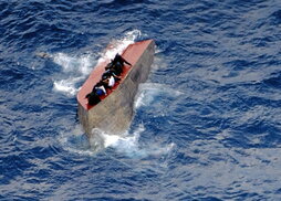 Migrantes sobre un bote volcado cerca de Libia.