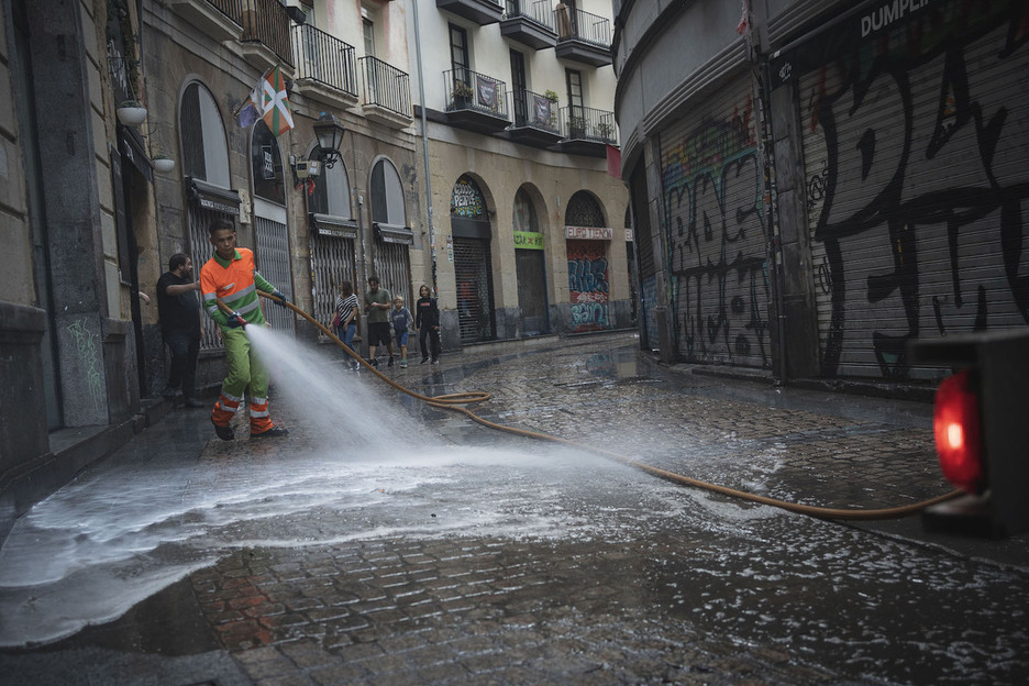Un operario de limpieza pasa la manguera en una calle de Alde Zaharra.