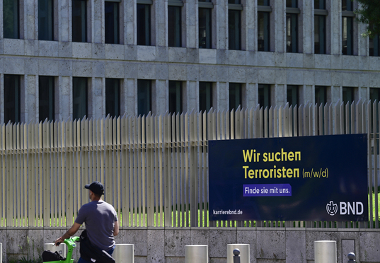 Un hombre pasa junto a un cartel de «Buscamos terroristas», colocado en la valla que rodea la sede del BND, en Berlín.
