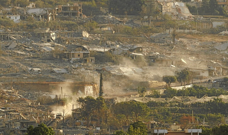 A la izquierda, imagen de la destrucción causada por el Ejército israelí en Al-Mansouri. A la derecha, varias personas observan desde Al-Haniya cómo, a lo lejos, destruyen su pueblo.