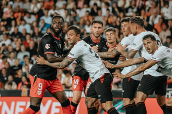 Jugadores de Athletic y Valencia aguardan el balón en el área.
