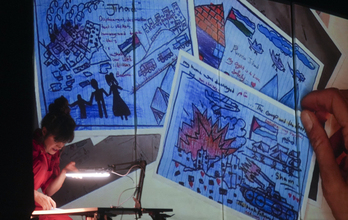 Adriana Salvo, en un ensayo, con las proyecciones de los dibujos enviados por niños de Gaza.