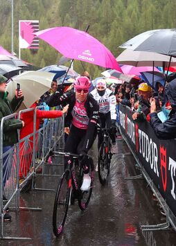 Protegido por un paraguas, Tadej Pogacar se dirige al nuevo punto de salida de la decimosexta etapa del Giro.